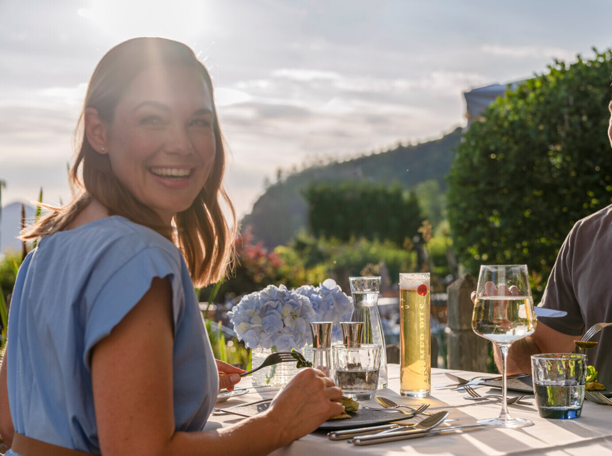 Junge Dame genießt kulinarische Köstlichkeiten auf der Sonnenterrasse des Wellnesshotels Ebner's Waldhof im Salzburger Land.