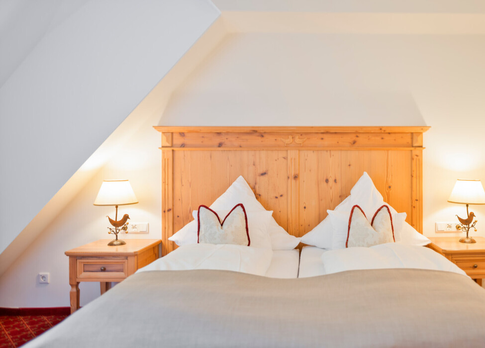Großzügiges Doppelbett mit Holz in der Osterhornsuite des Hotels Ebner's Waldhof am Fuschlsee.